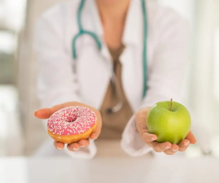 Ärztin zeigt Donut und Apfel