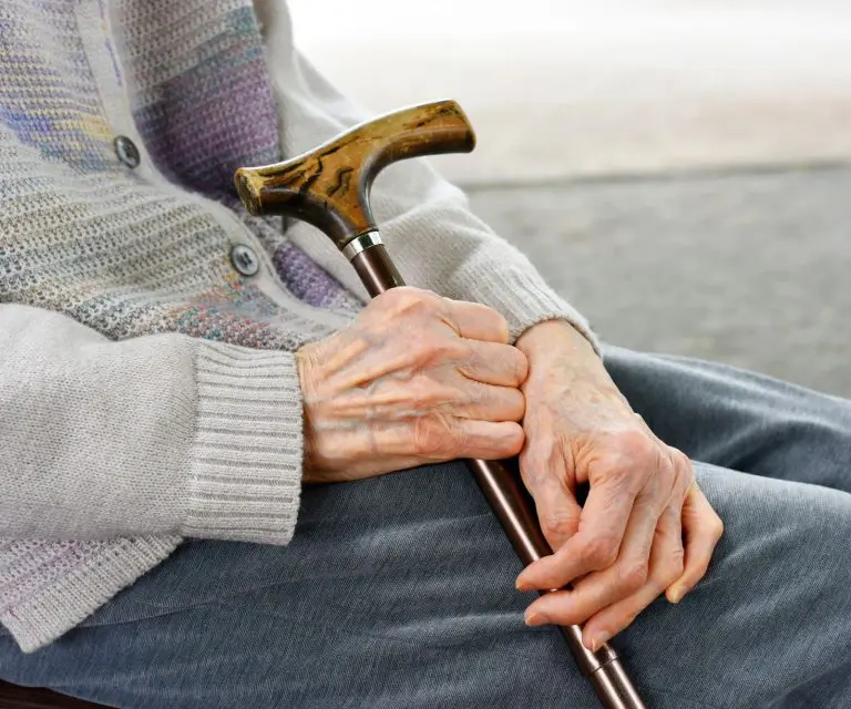 Gebrechlicher Senior mit Gehstock in der Hand